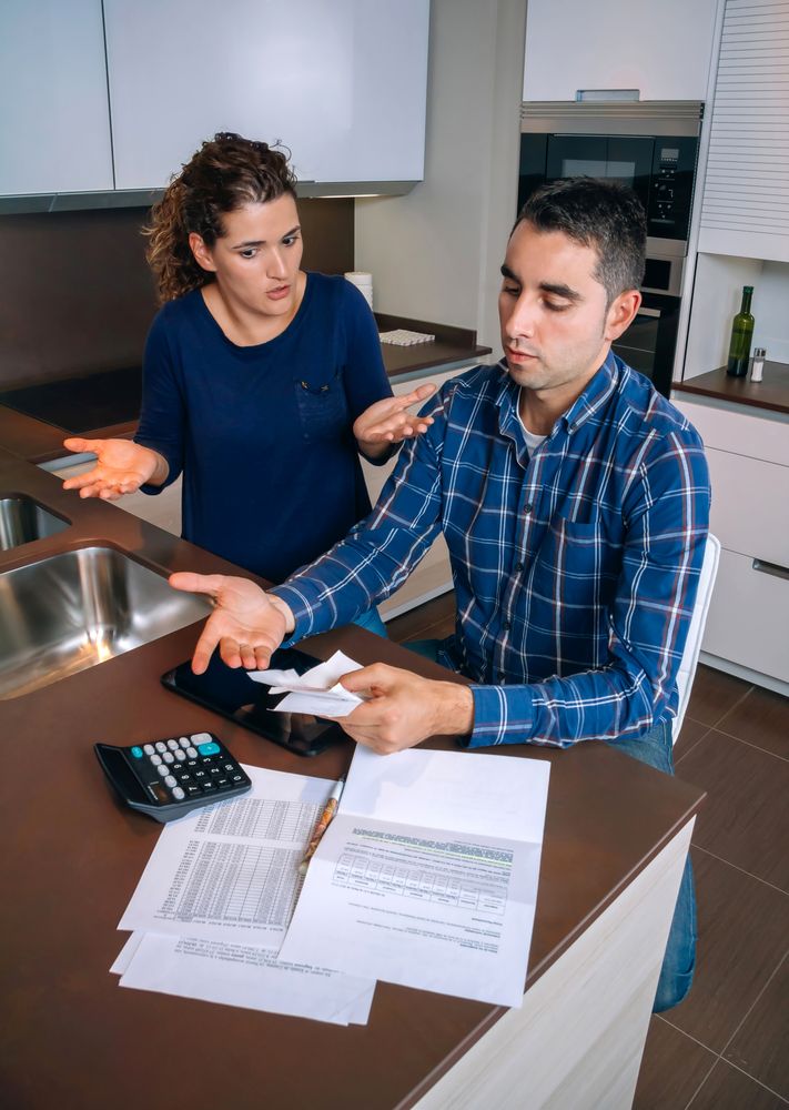 Couple arguing over their bills together in the kitchen, vertical