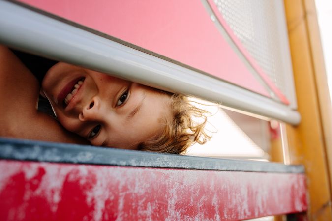 Close up of a boy looking through an opening of a signage frame