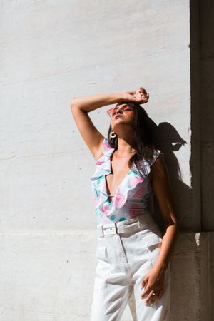 Dreamy stylish woman in sunglasses standing on city street