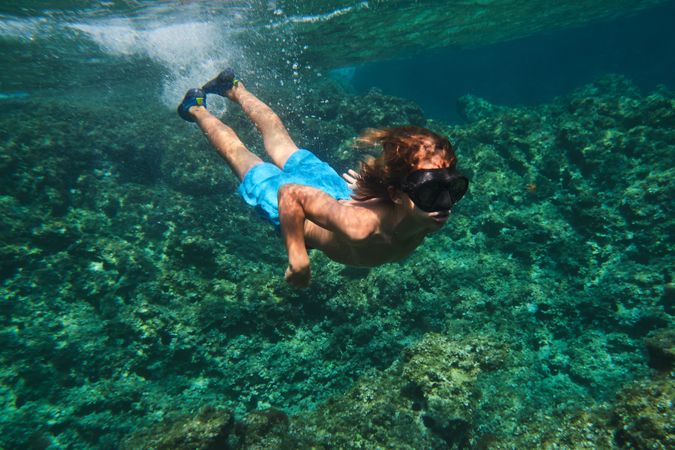 Boy in black goggles swimming underwater