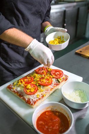 Unrecognizable chef preparing vegetarian focaccia with healthy ingredients in a restaurant kitchen