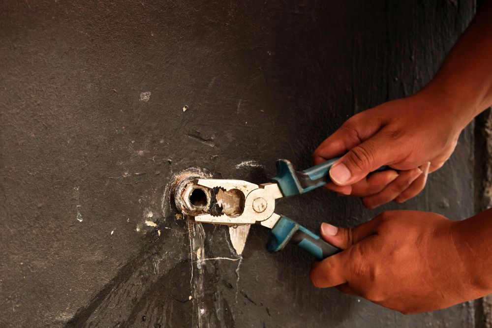 Hand of Asian Plumber Fixing Broken Water Tap on the Wall using Pliers