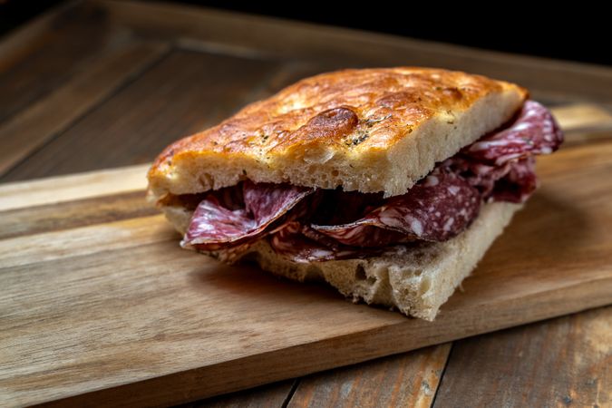 Rustic salami sandwich with crispy focaccia on a wooden board