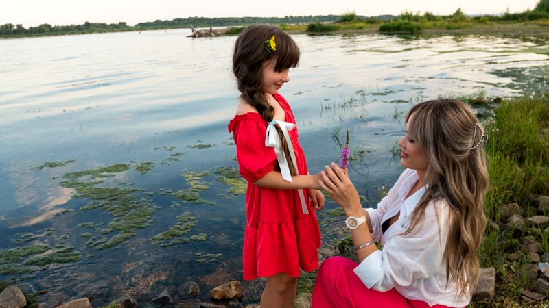 Mom and little daughter walking by the lake or pond