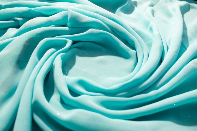 Spiral Twisted Turquoise wavy crumpled fabric with little sparkling dust and copy space in center, texture and  background.
