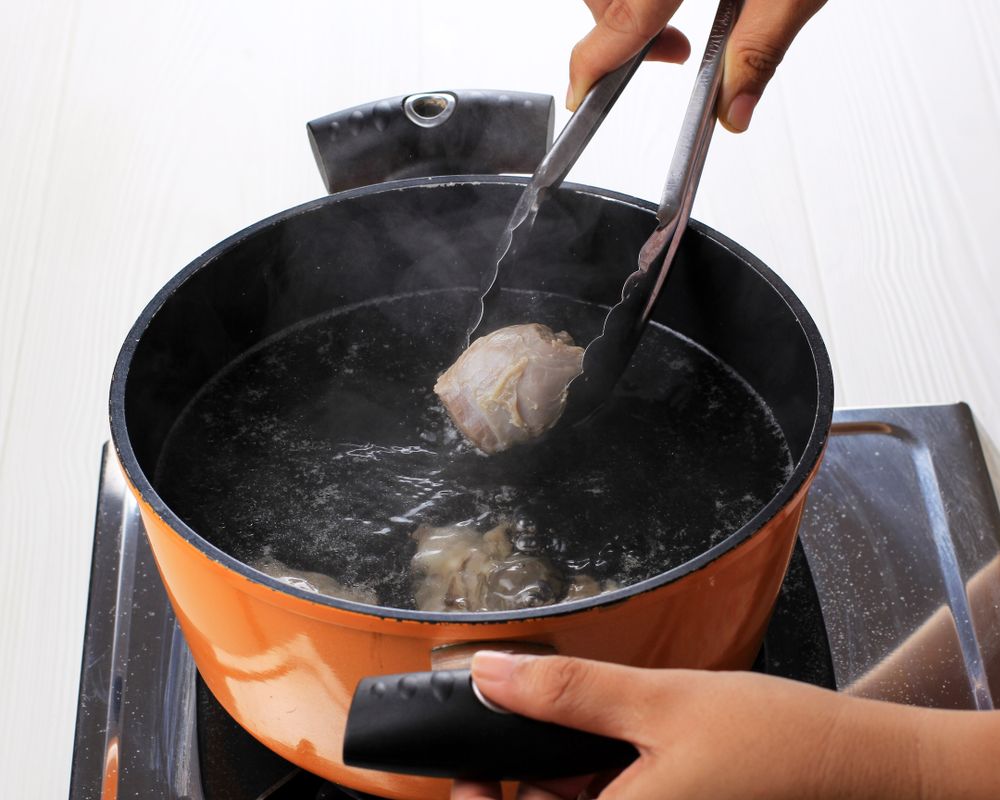 Person boiling beef in pot