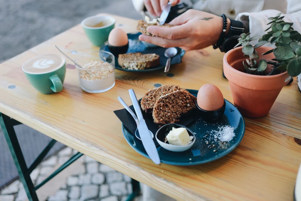 Man spreading butter on grainy toast with hard boiled egg