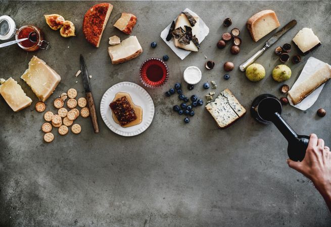 Wine snack variety, with hand pouring glass of wine, top view, copy space