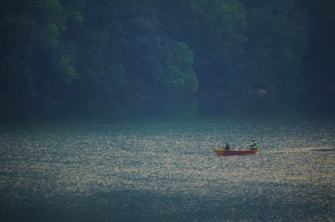 Two people on kayak on lake near trees