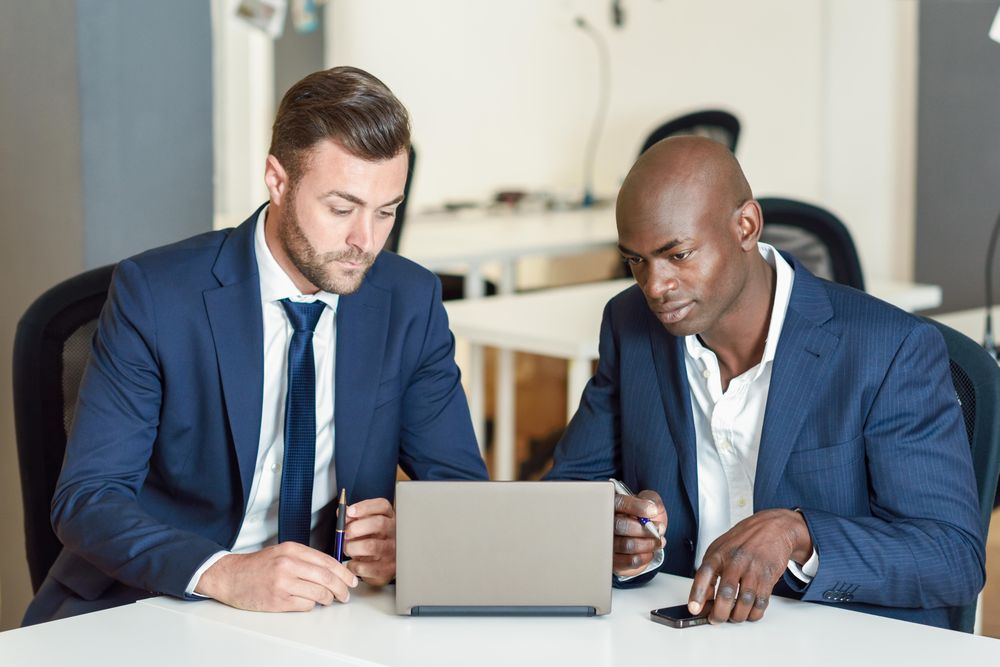 Two men wearing blue suits working in an office