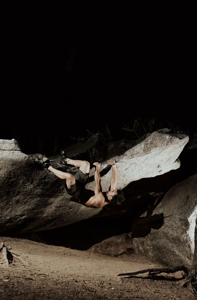 Man practicing rock climbing among large rocks in a forest