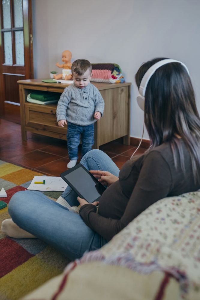 Pregnant using the tablet while her son is playing