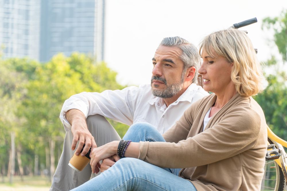 Older male and female sitting in the grass in public park