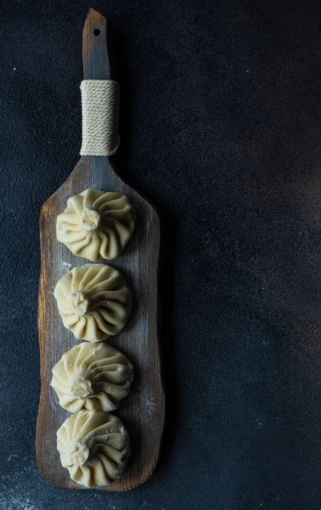 Top view of traditional Georgian khinkali dumplings served on wooden board on dark counter