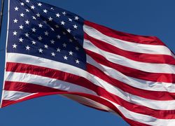 American Flag Waving In Wind Against a Deep Blue Sky.