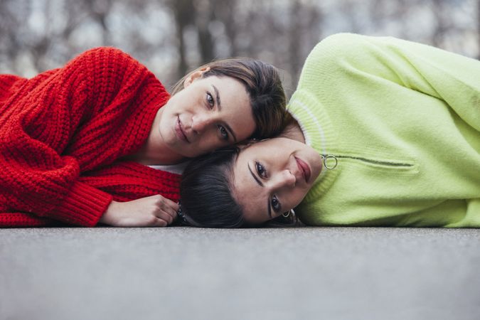 Women in sweaters lying on asphalt