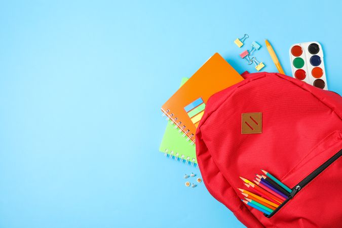Flat lay composition with backpack and school supplies on color background