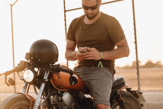 Man sitting on motorcycle and surfing mobile
