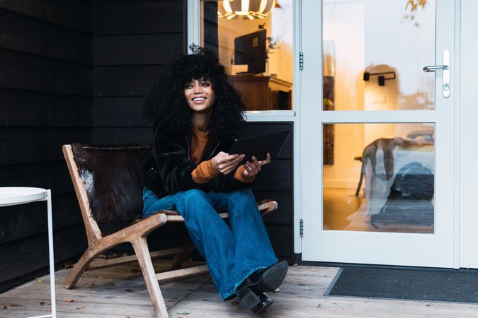 Smiling Black woman with tablet on veranda