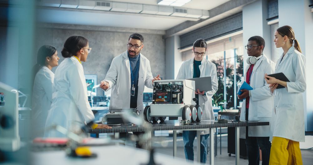Engineers In Lab Coats Discussing an Automated AI Robotic Delivery Assistant, Using Laptop, Tablet Computer