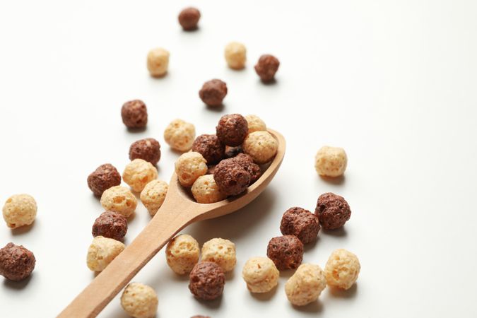 Spoon with corn balls on neutral background