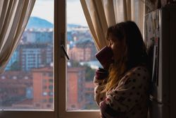 Woman enjoying hot beverage near fridge
