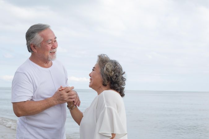Mature Asian couple smiling together at the beach