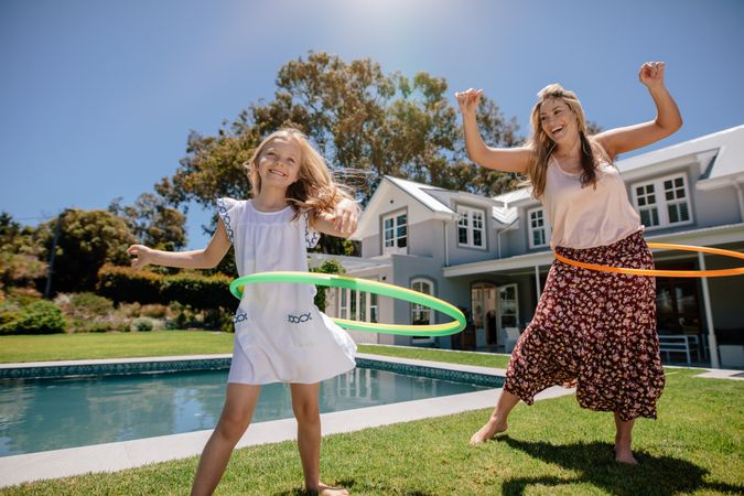Playful mother and daughter hula hooping on a sunny day