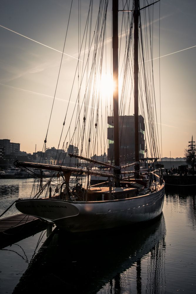 Boat docked by shoreline at sunset