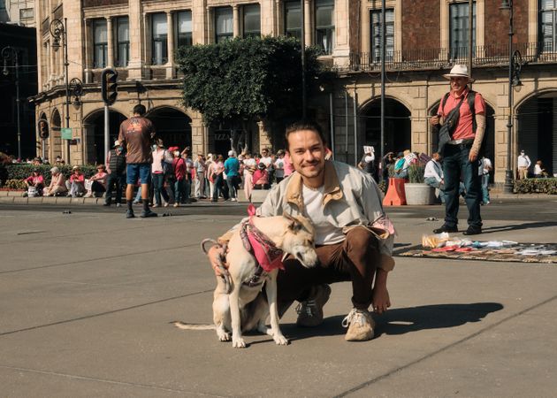 Mexico City, Mexico - February 26th, 2022: Man with cute dog with rally in background in Mexico City