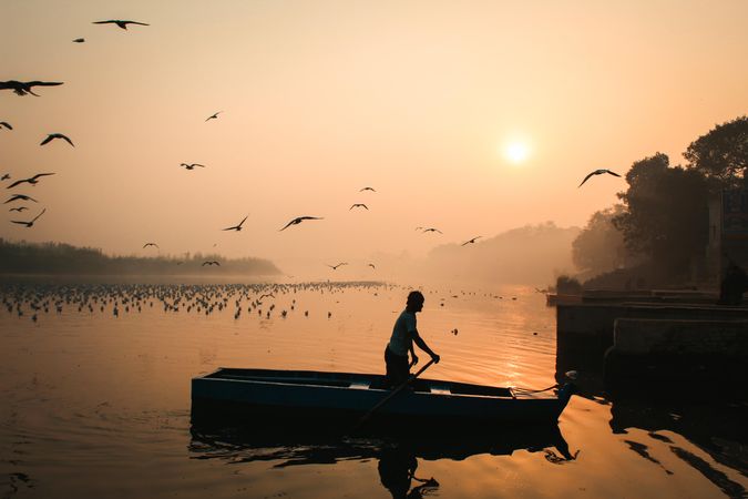 Man on paddling boat during golden hour