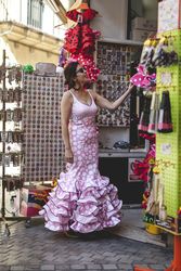 Interested woman in flamenco dress gazing at souvenir shop