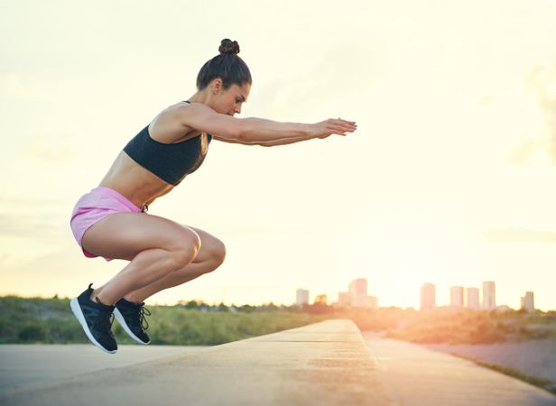 Woman doing box jumps with city in background