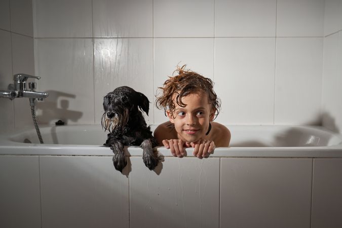 Boy with dog in bathtub