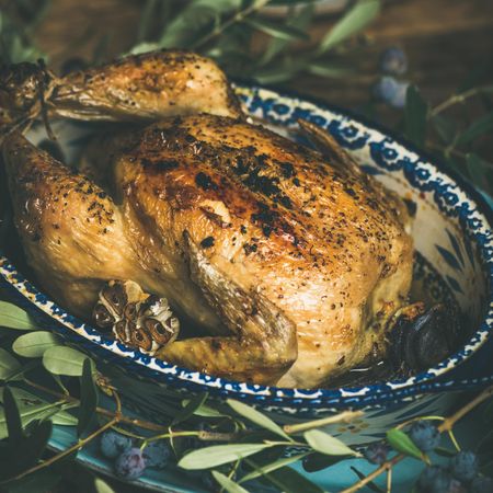 Close up of centerpiece of roast chicken with decorative branches, square crop