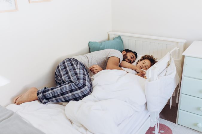Man sleeping with his son on bed