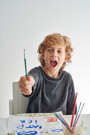 Astonished boy looking at paintbrush