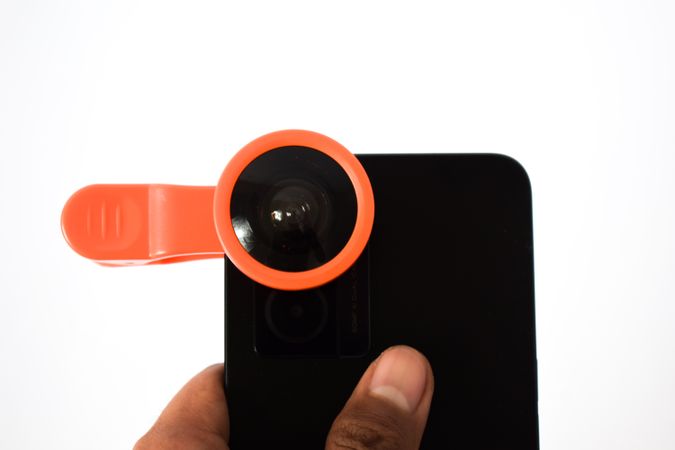 Hand holding smartphone with snap on lens accessory