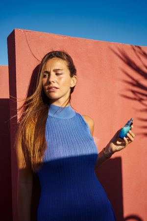 Woman on a red building holding perfume