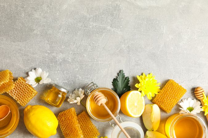 Flat lay with honey, flowers and fruits on grey background, copy space