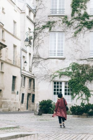 Back view of person wearing red coat walking near building