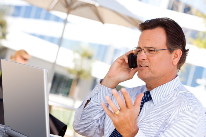 Businessman Talking on Cell Phone Using Laptop