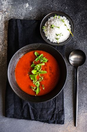 Top view of gazpacho soup served in dark bowl with salt