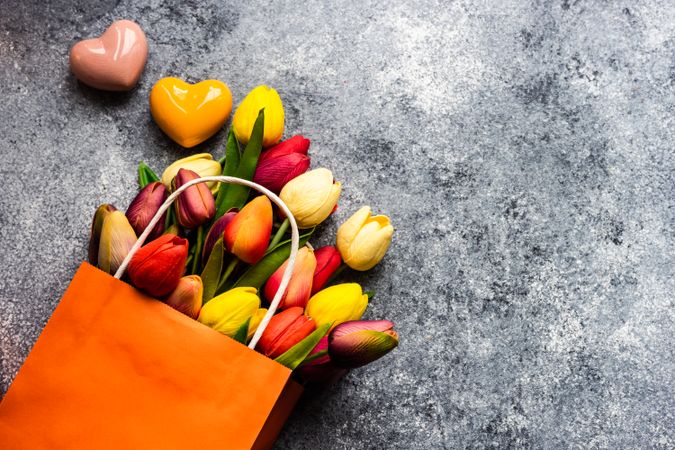 Ceramic heart ornaments on grey counter with bag of fresh tulips