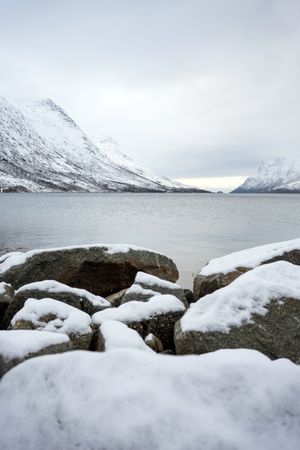 Scenic view from sea stones on snowy mountains