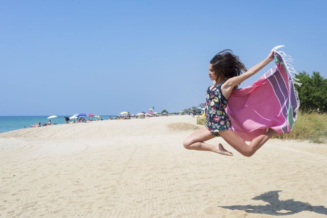 Woman jumping with beach wrap