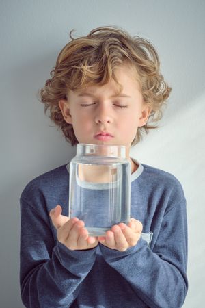 Little boy holding glass bottle of water