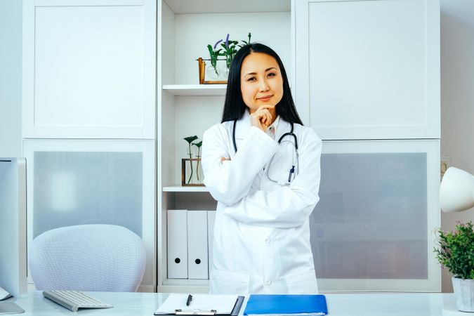 Contemplative Asian doctor thinking about something in her office