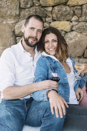 Happy couple sitting on a terrace while bonding and enjoying a cup of wine