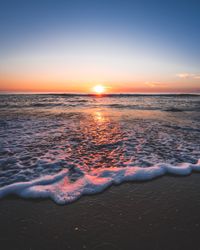 Ocean waves on sandy shore during sunset